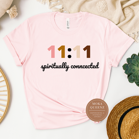 A pink unisex t-shirt with the text '11:11 Spiritually Connected' printed on the front, displayed flat with a graphic of a plant and a straw hat.
