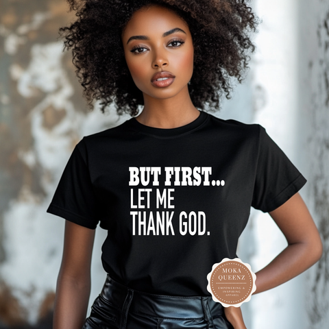 Woman wearing a black t-shirt with text 'But first... let me thank God' and a visible brand logo.