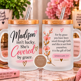 Two frosted glass mugs with bamboo lids and metal straws displayed side by side on a marble surface. The left mug reads 'Madison isn't lucky.