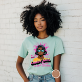 Woman wearing a light blue t-shirt with a graphic design against a white brick wall.