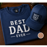 Navy blue t-shirt and cap with 'Best Dad Ever' text on a wooden surface.