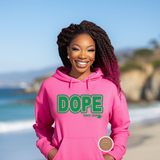 Woman wearing a pink hoodie with 'DOPE' text on a beach