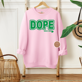 Pink sweatshirt with green text 'DOPE SINCE 1908' on a wooden hanger against a white wall.