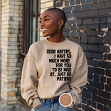 Person wearing a beige sweatshirt with text in front of a brick wall
