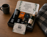 Gift set for Father's Day with 'Best Dad Ever' mugs, a bottle of wine, and a card on a wooden surface.