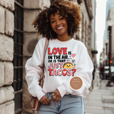 Woman wearing a white sweatshirt with a humorous taco-themed design, standing on a city street.