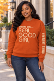 A woman wearing a burnt orange crewneck sweatshirt with the text 'SPECIAL GIRL.