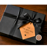 Black gift box with a brown tag and Moka Queen logo on a wooden surface