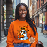 Woman wearing an orange sweatshirt with a Halloween-themed design on a city street.