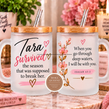 Two frosted glass mugs with bamboo lids and metal straws displayed side by side on a marble countertop. The left mug reads 'Tara survived the season that was supposed to break her.