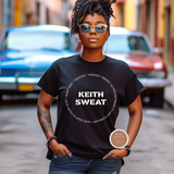 Person wearing a black t-shirt with 'KEITH SWEAT' text, standing on a street with vintage cars in the background.