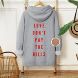Gray hoodie with red text 'LOVE DON'T PAY THE BILLS' on a wooden hanger against a neutral wall.
