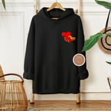 Black hoodie with a red and yellow graphic on a wooden hanger against a white wall.