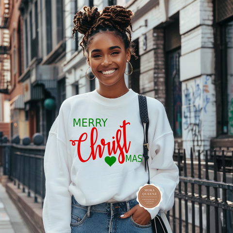 Woman wearing a white sweatshirt with 'Merry Christmas' text, standing on a city street.