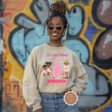 Woman wearing a beige sweatshirt with a Christmas-themed design in front of a colorful mural.