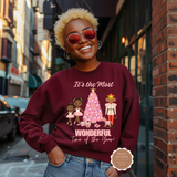 Woman wearing a maroon sweatshirt with Christmas-themed design on a city street.