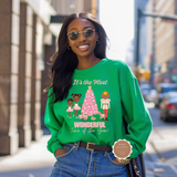 Woman wearing a green sweatshirt with a Christmas-themed graphic on a city street.