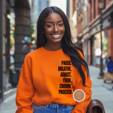 Woman wearing an orange sweatshirt with motivational text on a city street