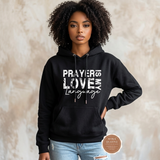Model wearing a black Prayer Is My Love Language hoodie with distressed white typography