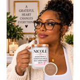 A woman wearing glasses and a cream knit cardigan holds a frosted glass mug with a rose-gold lid and straw. The mug is printed with the name 'NICOLE' and a printed quote.