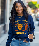Woman wearing a blue sweatshirt with a sun and moon design and text, standing on a city street.