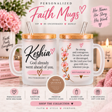 Two personalized Faith Mugs with bamboo lids and straws, shown on a styled background with pink flowers, candles, and text overlays explaining the personalization options. The mugs are frosted white with black and pink text and floral designs.