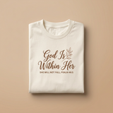 Folded cream God Is Within Her shirt with brown script and botanical branch, Psalm 46:5