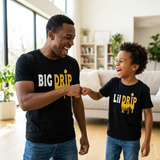 Dad and son fist bumping, both wearing black Big Drip and Lil Drip matching shirts