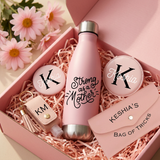Close-up of the Strong as a Mother water bottle, Keshia monogram mirror, KM sanitizer keychain, and Keshia's Bag of Tricks pouch in the gift box