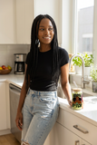 Woman holding a 100% That B*tch graphic glass with iced matcha in a sunlit kitchen.