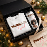 Close-up of the Brown Skin Girl sweatshirt and white matching tumbler inside the black gift box with the tote beside it