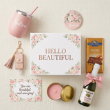 Hello Beautiful personalized gift box flat lay with the Madison tumbler, floral mirror, candle, sanitizer keychain with tassel, full-size Ghirardelli caramel candy bar, mini Martinelli's Sparkling Cider, and floral card