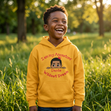 Laughing Black boy in a park wearing a gold I Am My Ancestors Wildest Dream hoodie personalized with the name Dante