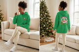Green Grinchmas hoodie front and back on a woman with coordinated sneakers and hot cocoa in a cozy Christmas setting.
