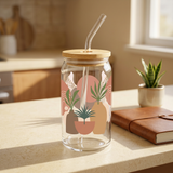 Boho botanical glass with terracotta plant-pot artwork, bamboo lid and glass straw on a sunlit kitchen counter.