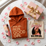 Flat lay of the Special Girl Gift Box contents: hoodie with matching orange drawstrings, affirmation tumbler, tote bag, and gift box lid with rose petals