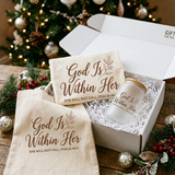Close-up of the God Is Within Her shirt and frosted glass can cup inside the white gift box with the matching tote beside it