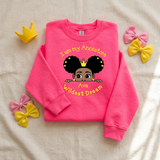 Bright safety pink I Am My Ancestors Wildest Dream girls sweatshirt flat lay with a yellow toy crown and satin bows