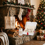 God Is Within Her Christmas Gift Box by a fireplace and Christmas tree with the matching shirt, cup, and tote