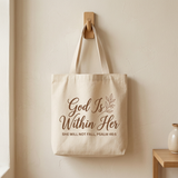 God Is Within Her beige canvas tote bag hanging on a wooden hook, Psalm 46:5 design