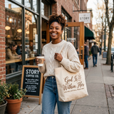 Smiling Black woman carrying the God Is Within Her tote bag outside a coffee shop