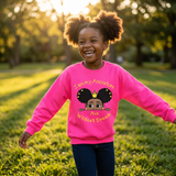 Laughing Black girl with afro puffs twirling in a park wearing a bright safety pink I Am My Ancestors Wildest Dream sweatshirt with the name Ava