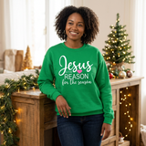 Black woman leaning beside a console in a green Jesus Is the Reason for the Season sweatshirt with a pink heart.